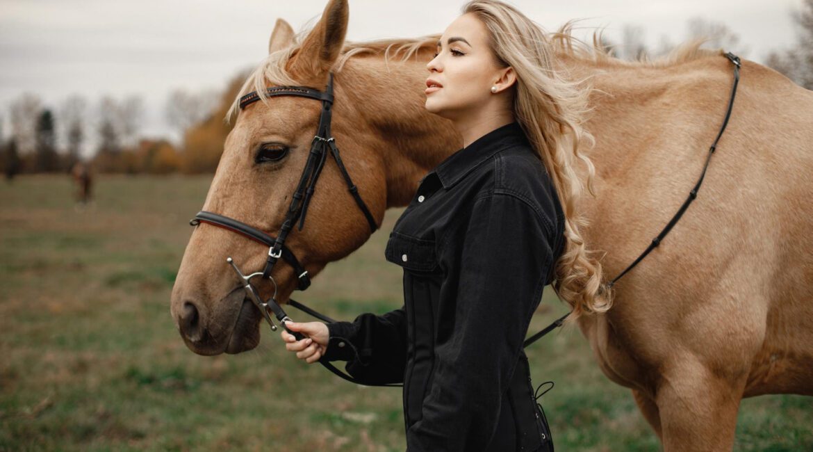 blonde woman brown horse standing field woman wearing black clothes woman touching horse